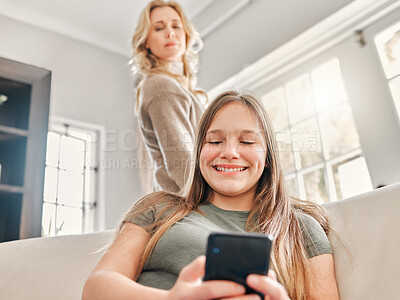 Buy stock photo Shot of a mature mother sneakily checking what her daughter's doing on her phone at home