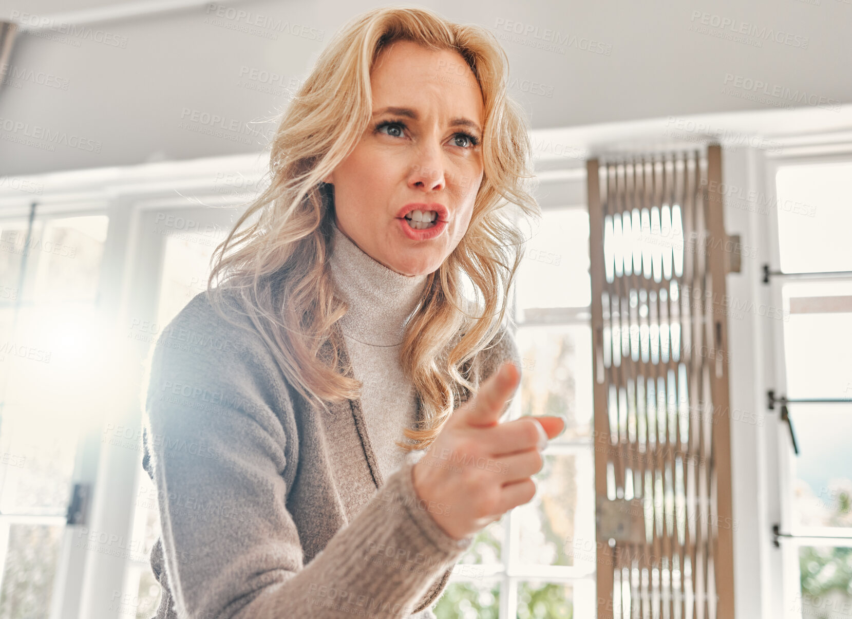 Buy stock photo Shot of a mature woman looking upset while scolding someone at home