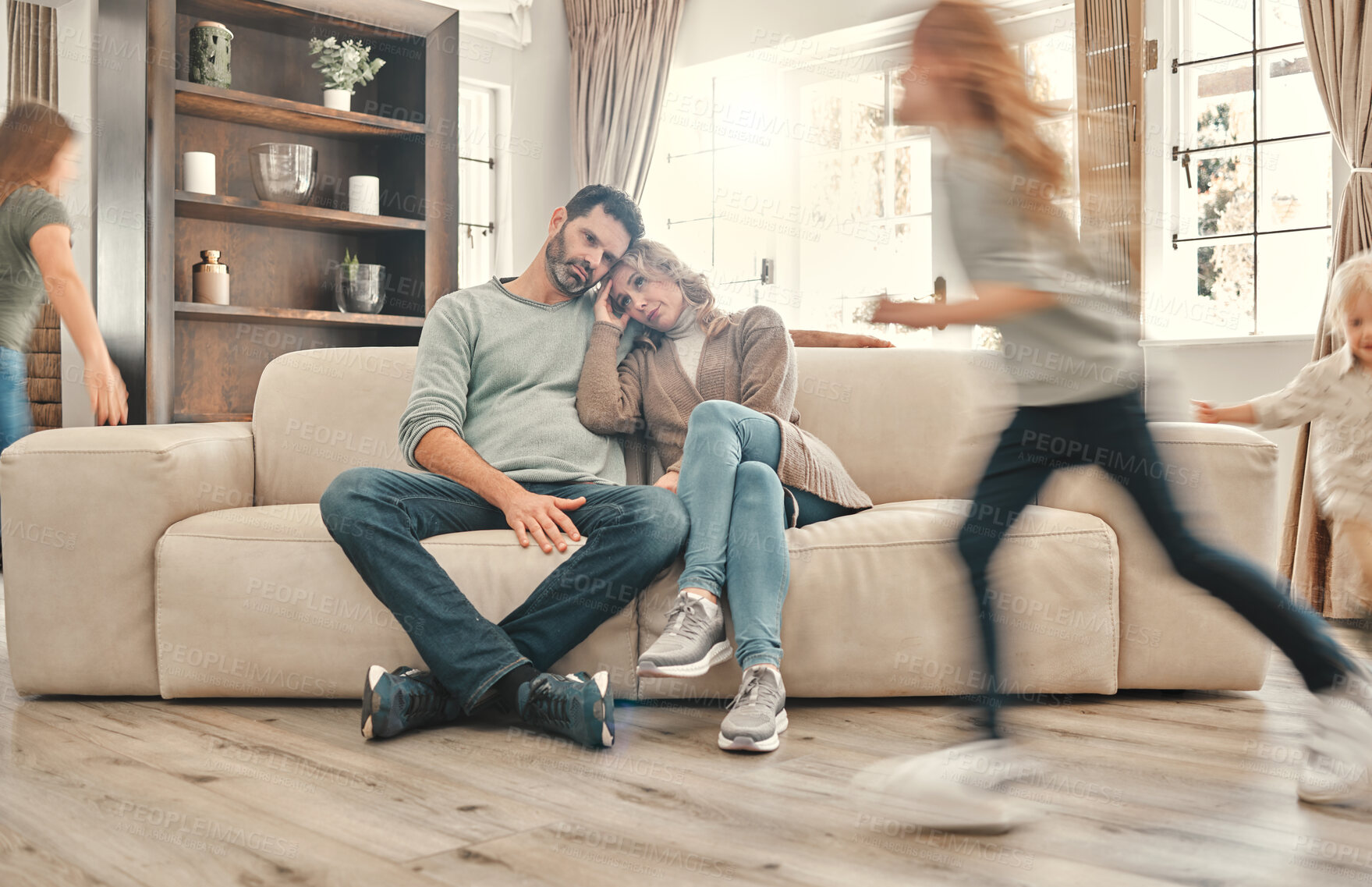 Buy stock photo ADHD, kids running and exhausted parents on sofa in living room of home with anxiety or stress. Autism, energy or noise with tired mother and father watching excited children in apartment together