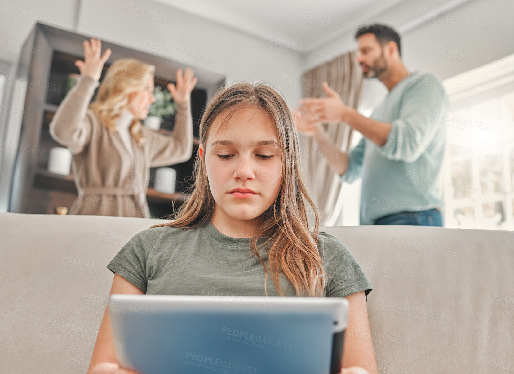 Buy stock photo Shot of a young girl using a digital tablet while her parents argue at home