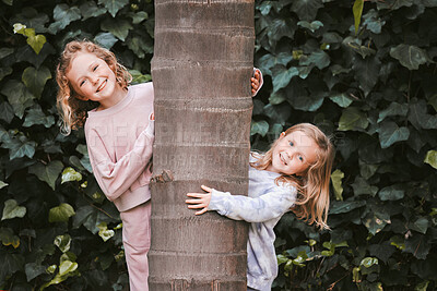 Buy stock photo Shot of two adorable little girls hugging a tree in a garden