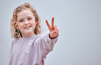 Buy stock photo Studio shot of a little girl making a peace sign against a grey background