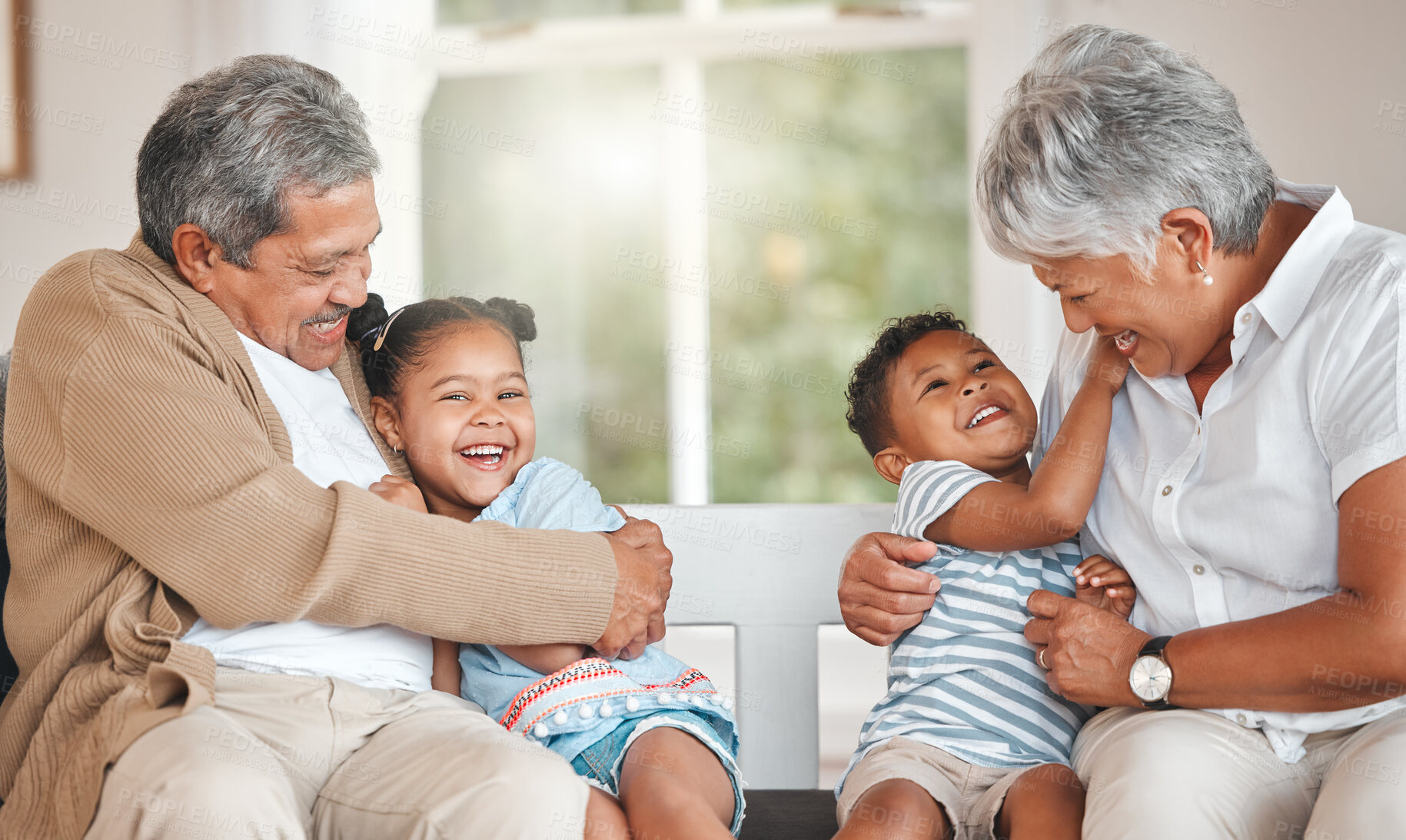 Buy stock photo Shot of grandparents bonding with their grandchildren on a sofa at home