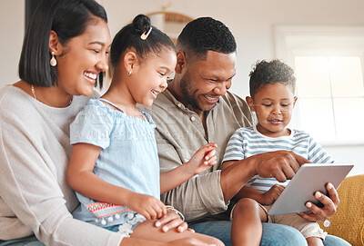 Buy stock photo Shot of a young family happily bonding while using a digital tablet together on the sofa at home