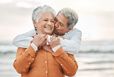 Buy stock photo Happy senior couple, hug and beach with smile, bonding and kiss on cheek for romance, love and vacation. Elderly man, woman and embrace with happiness, retirement and travel by ocean for holiday