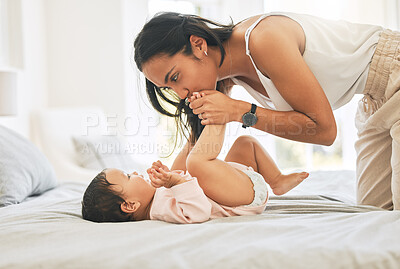 Buy stock photo Mother, baby and kiss feet in a family home for bonding, happiness and quality time. Woman or mom and girl child relax together in bedroom for development, trust and support or care on mothers day