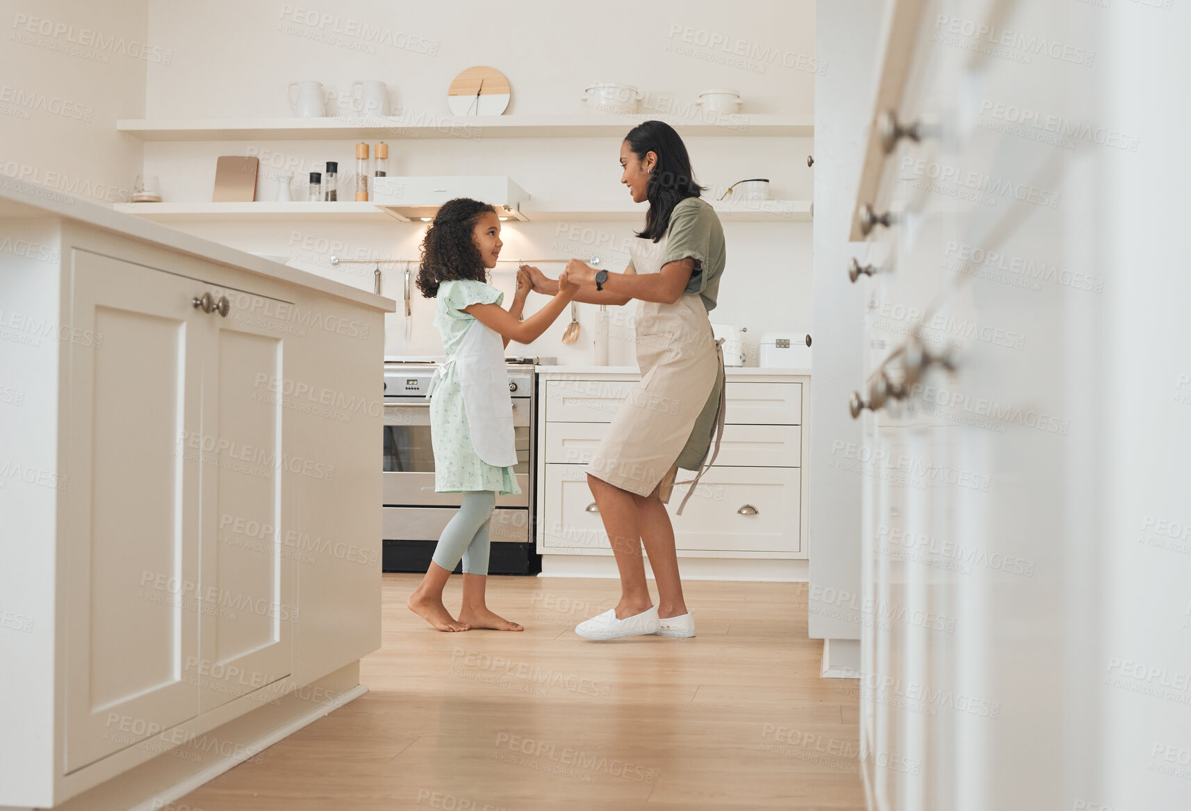 Buy stock photo Shot of a mother and daughter dancing around the kitchen while baking