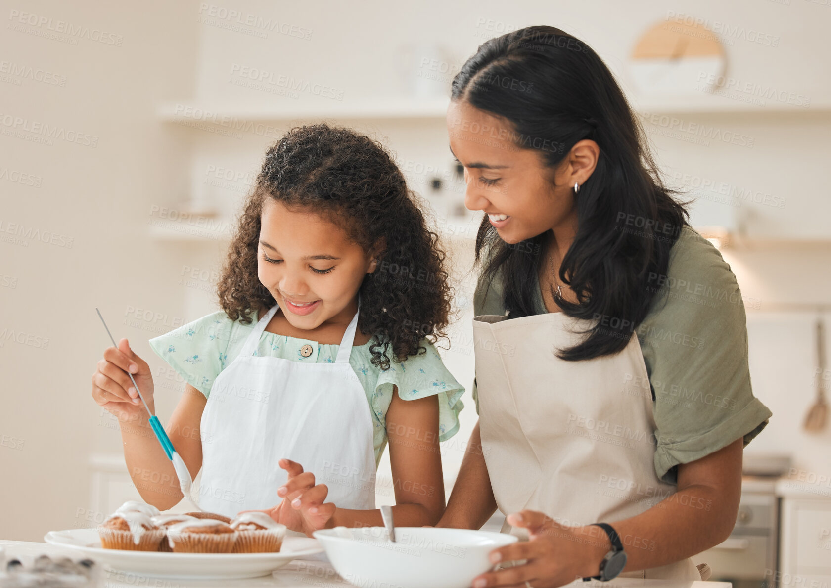 Buy stock photo Shot of a mother and daughter frosting freshly baked cupcakes