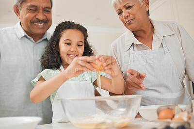 Buy stock photo Shot of two grandparents helping their granddaughter crack an egg into a bowl