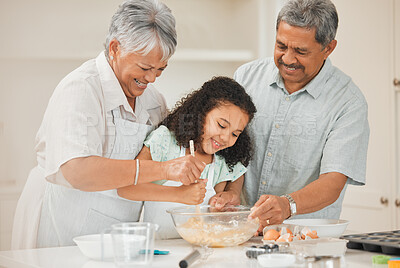 Buy stock photo Shot of grandparents helping their grandchild stir a bowl of muffin batter
