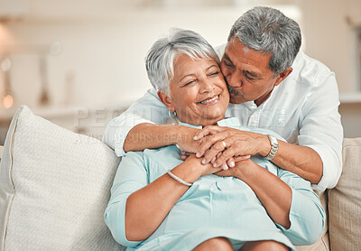 Buy stock photo Kiss, hug and senior couple in living room, smile and bonding of old man and woman with love. Lounge, sofa and embrace of elderly people with commitment to marriage, care and support in house