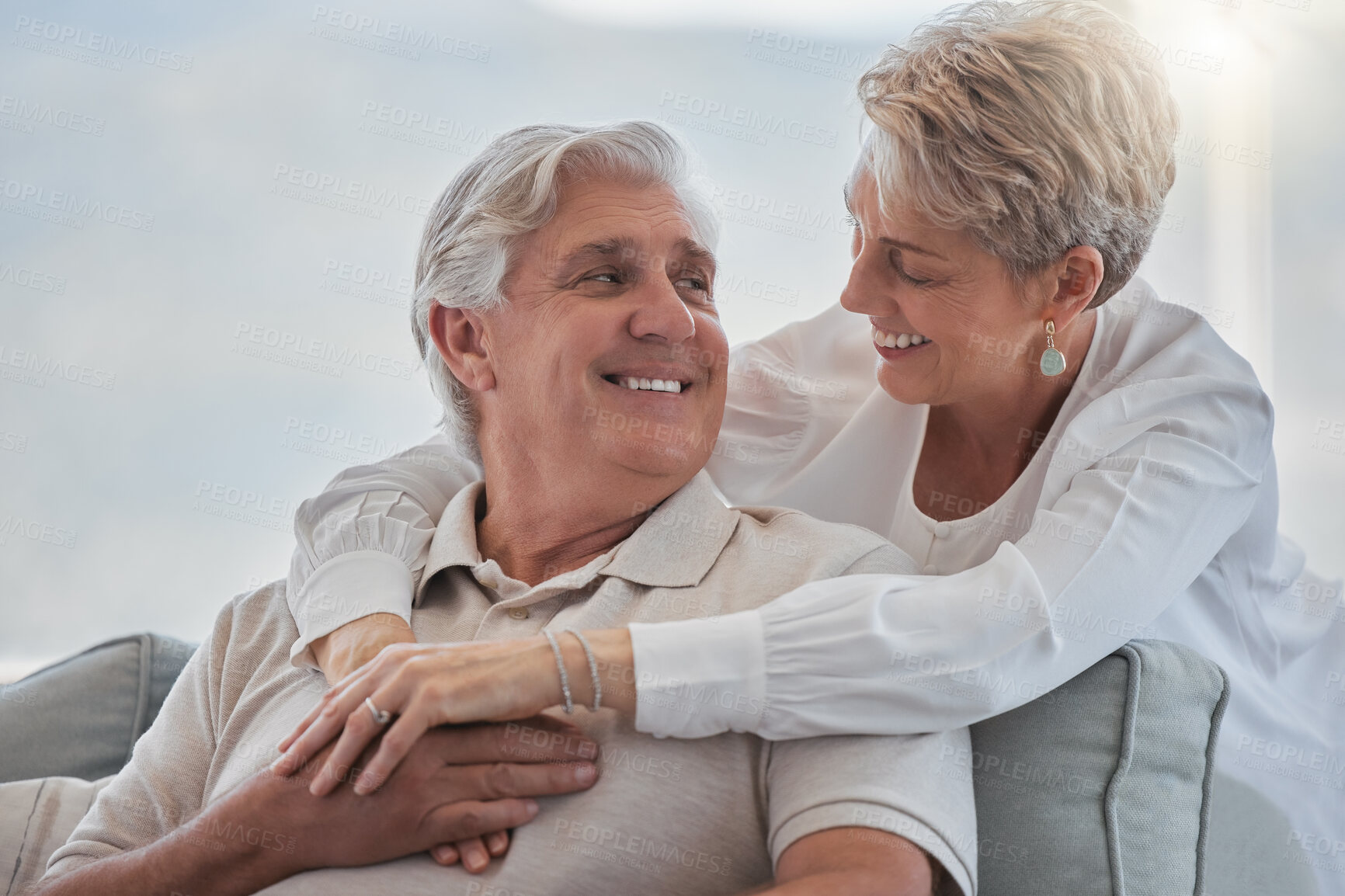 Buy stock photo Senior, couple and hug in home with love for romance, bonding or marriage commitment on sofa. Mature people, happy and trust embrace on couch in living room with loyalty, caring or affection in house