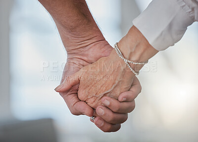Buy stock photo Cropped shot of an unrecognizable senior couple holding hands in their living room at home