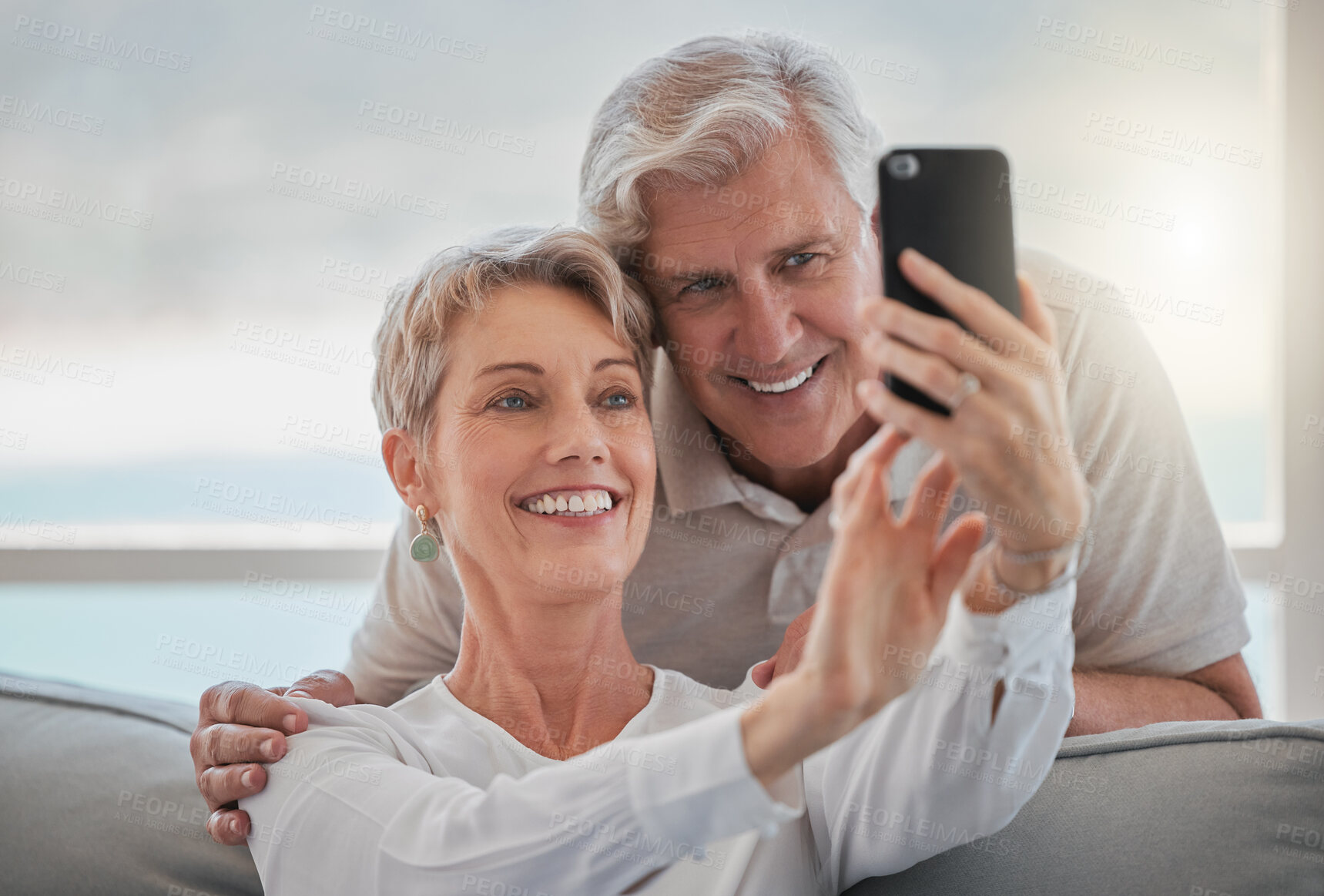 Buy stock photo Cropped shot of an affectionate senior couple taking selfies while relaxing in the living room at home