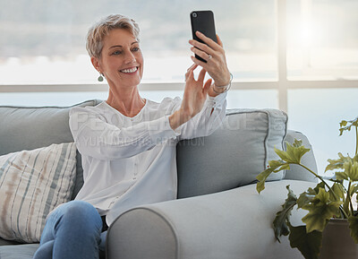 Buy stock photo Cropped shot of an attractive senior woman taking selfies while relaxing in her living room at home