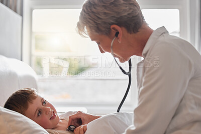 Buy stock photo Shot of a doctor examine a little boy with a stethoscope in bed at home