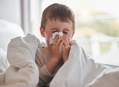 Buy stock photo Shot of a little boy feeling ill in bed at home and blowing his nose