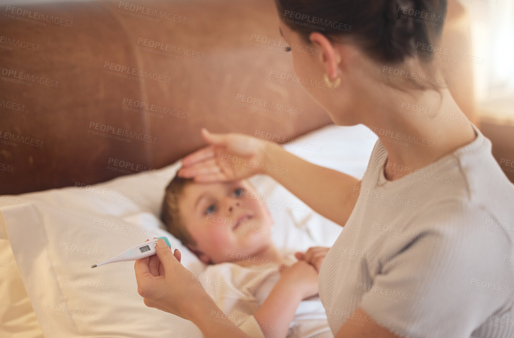 Buy stock photo Shot of a woman taking her little boy's temperature with a thermometer in bed at home