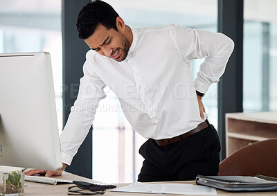 Buy stock photo Shot of a young businessman experiencing back pain at work
