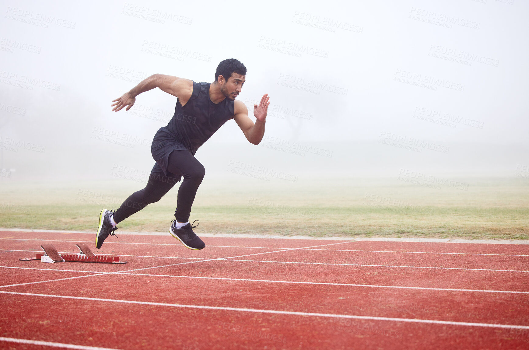 Buy stock photo Outdoor, exercise and man running at track for fitness, sports and training for competition. Mist, fog and Asian male athlete with speed at athletics field for cardio, workout and practice for race