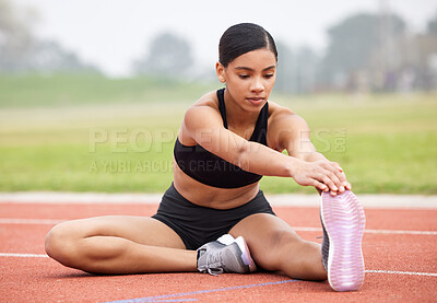 Buy stock photo Full length shot of an attractive young female athlete going through her warmups out on the track