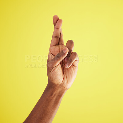 Buy stock photo Studio shot of an unrecognisable man crossing his fingers against a yellow background