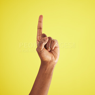 Buy stock photo Studio shot of an unrecognisable man pointing upwards against a yellow background