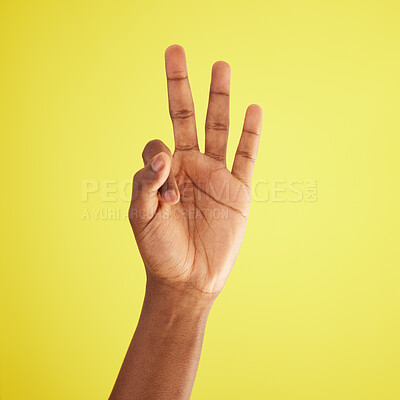 Buy stock photo Studio shot of an unrecognisable man showing three fingers against a yellow background