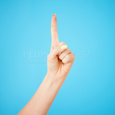 Buy stock photo Studio shot of an unrecognisable woman pointing upwards against a blue background