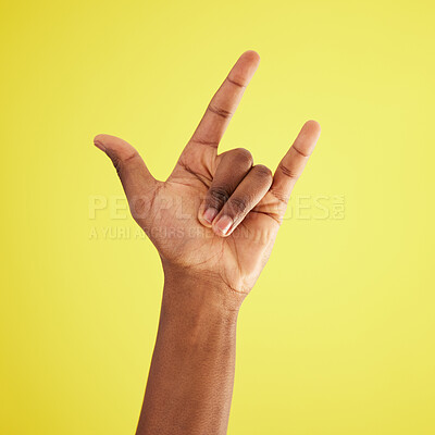 Buy stock photo Studio shot of an unrecognisable man making a horn sign against a yellow background
