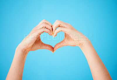 Buy stock photo Studio shot of an unrecognisable woman making a heart shaped gesture with her hands against a blue background