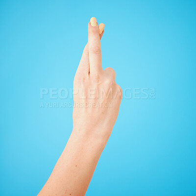 Buy stock photo Studio shot of an unrecognisable woman crossing her fingers against a blue background