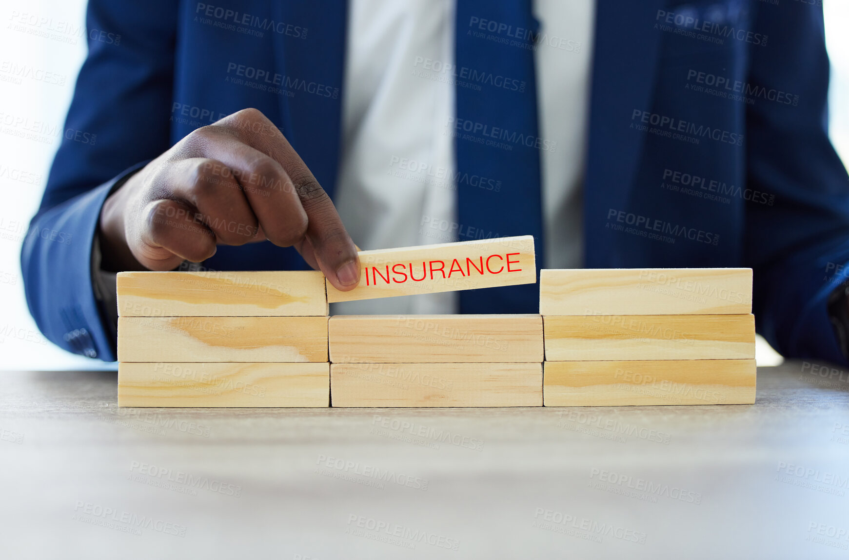 Buy stock photo Shot of an unrecognisable businessman assembling wooden blocks the word ‘insurance’ on them