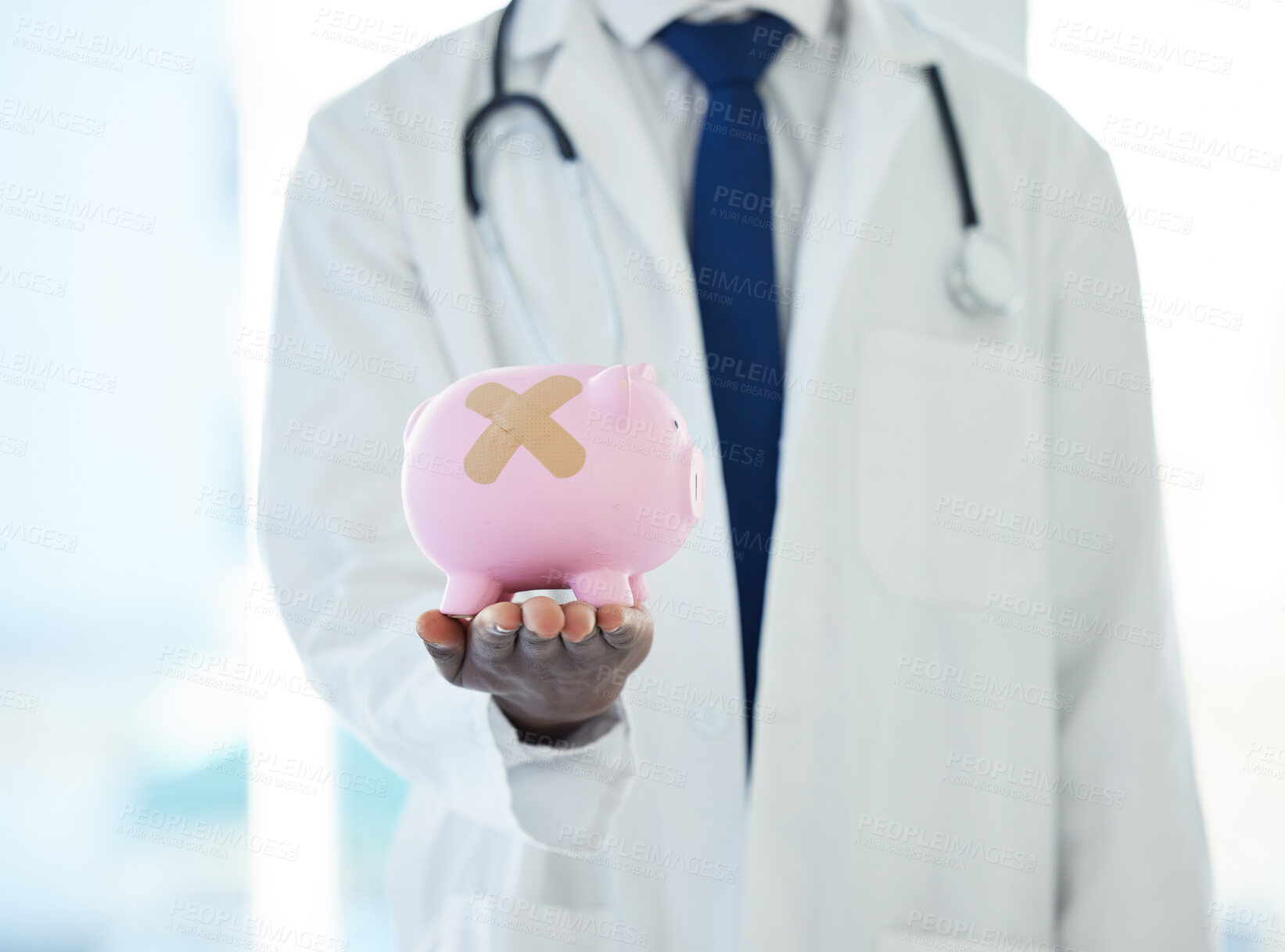 Buy stock photo Shot of an unrecognisable doctor holding a piggybank with a band aid covering it