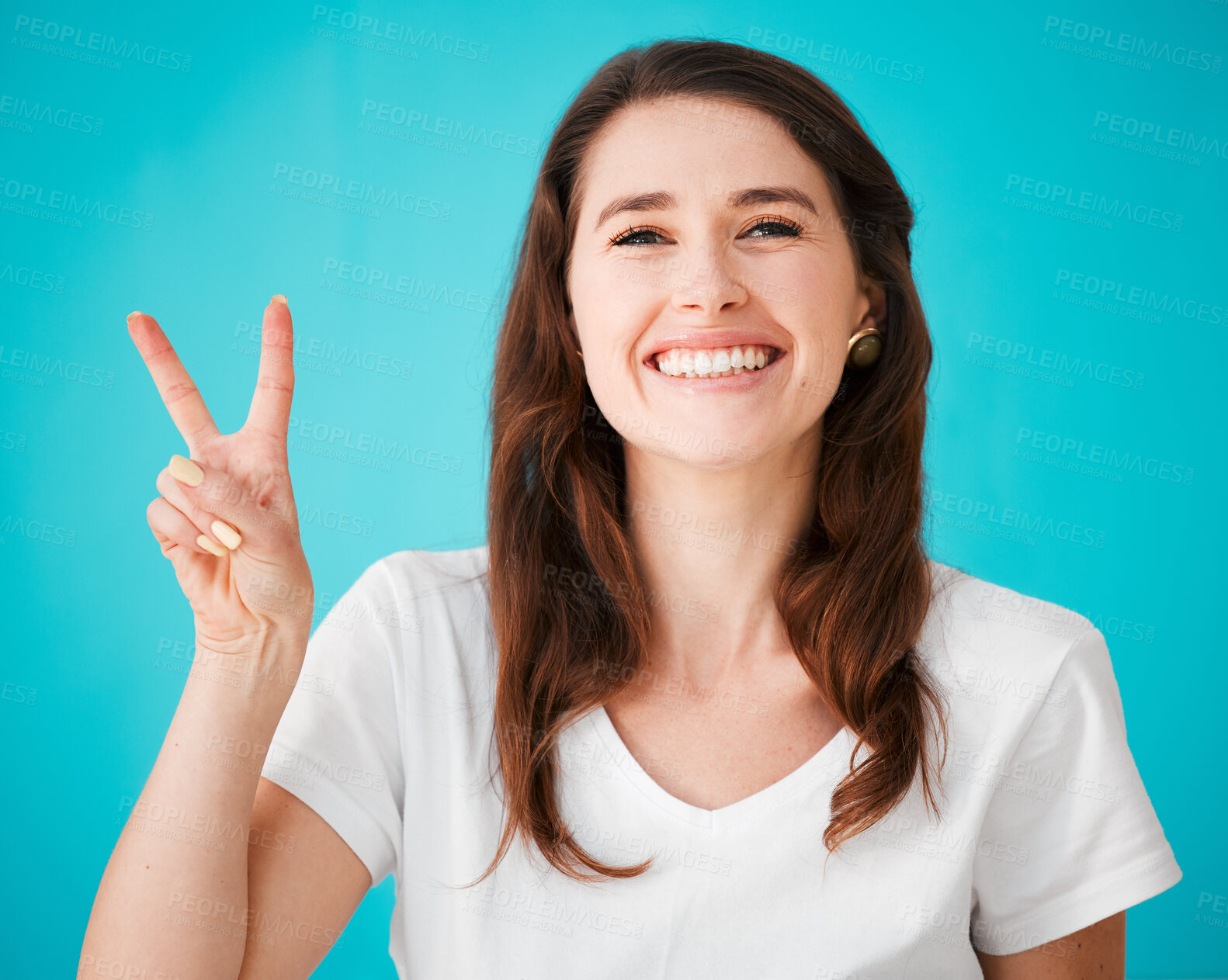 Buy stock photo Happy, woman and portrait with peace sign in studio for support, positivity and kindness emoji. Confident smile, female person and hand with v gesture for care, feedback and unity on blue background