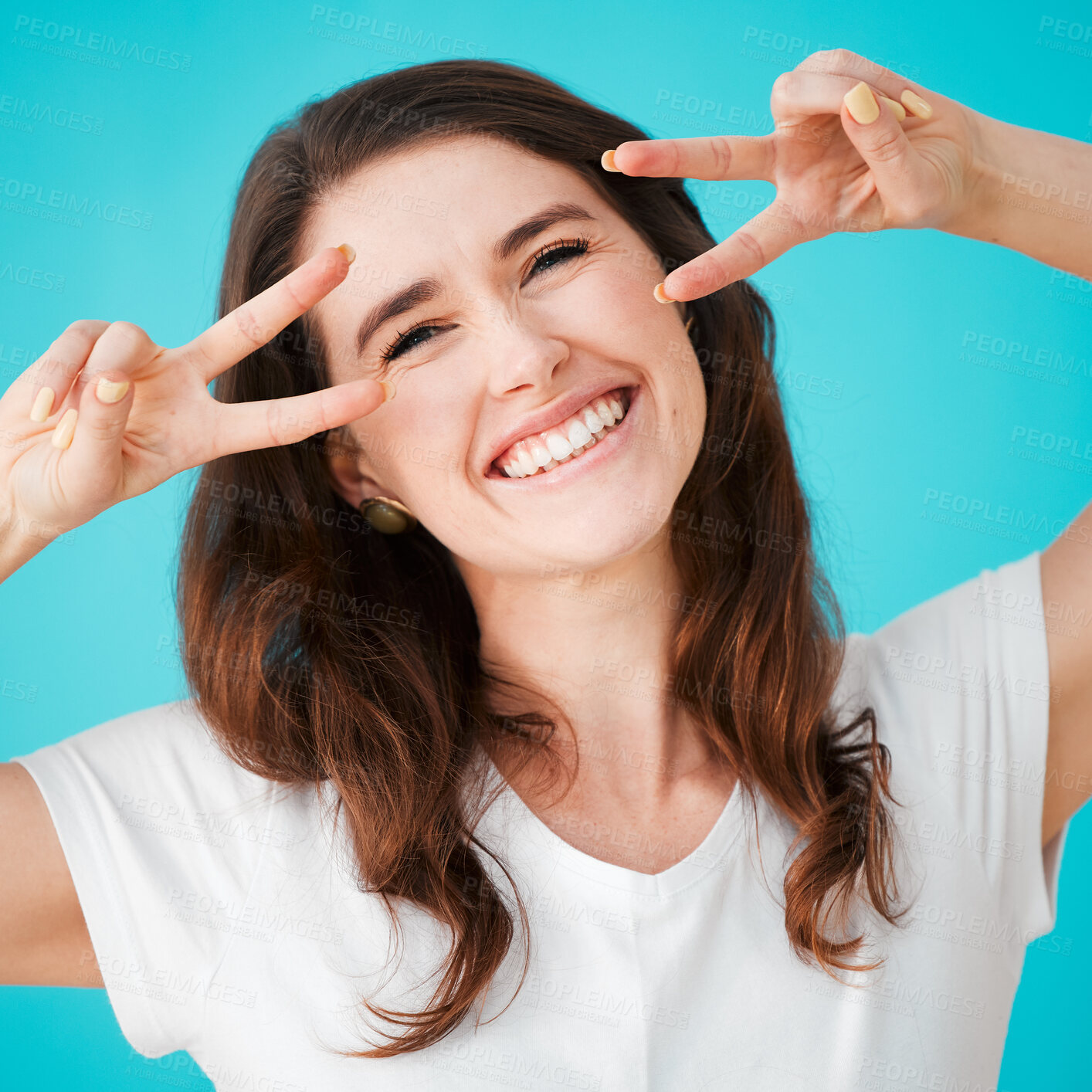 Buy stock photo Studio, happy woman and peace sign at eyes for portrait, excited and freedom in youth. Person, smile and hand gesture on blue background for energy, confidence and creative reaction to good news