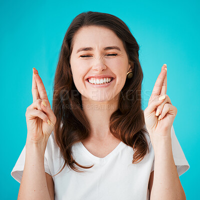 Buy stock photo Fingers crossed, good luck and hope with woman on blue background for superstition or wish. emoji, eyes closed and giveaway with happy person isolated in studio in anticipation of competition win 