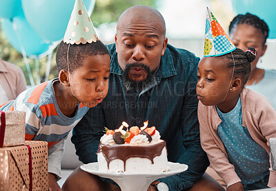 Buy stock photo Shot of a man and two children blowing out candles on a birthday cake