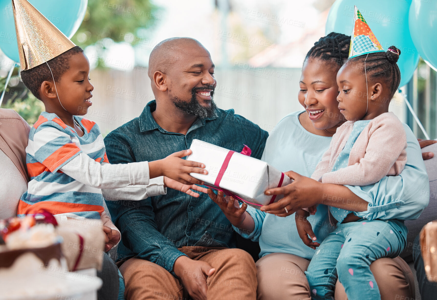 Buy stock photo Shot of a family handing over gifts during a birthday party