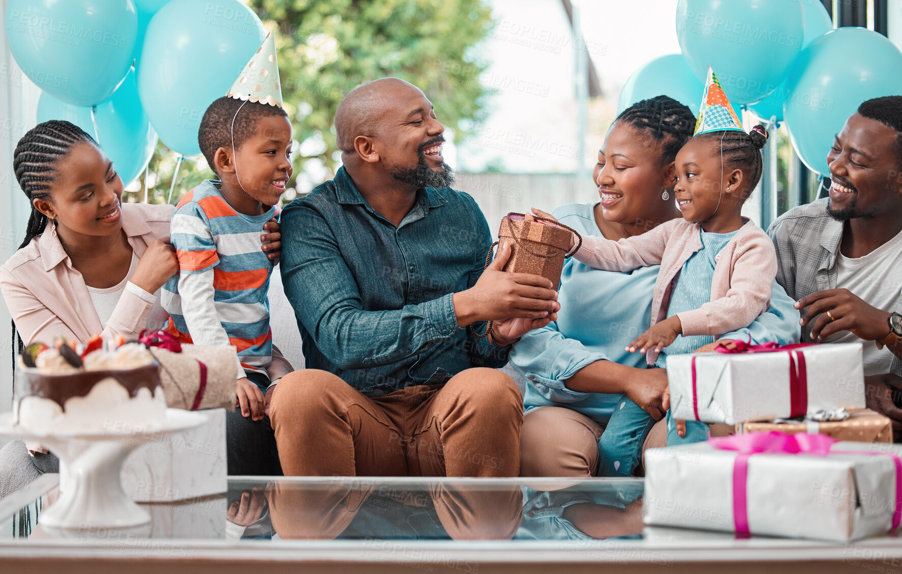 Buy stock photo Shot of a family handing over gifts during a birthday party