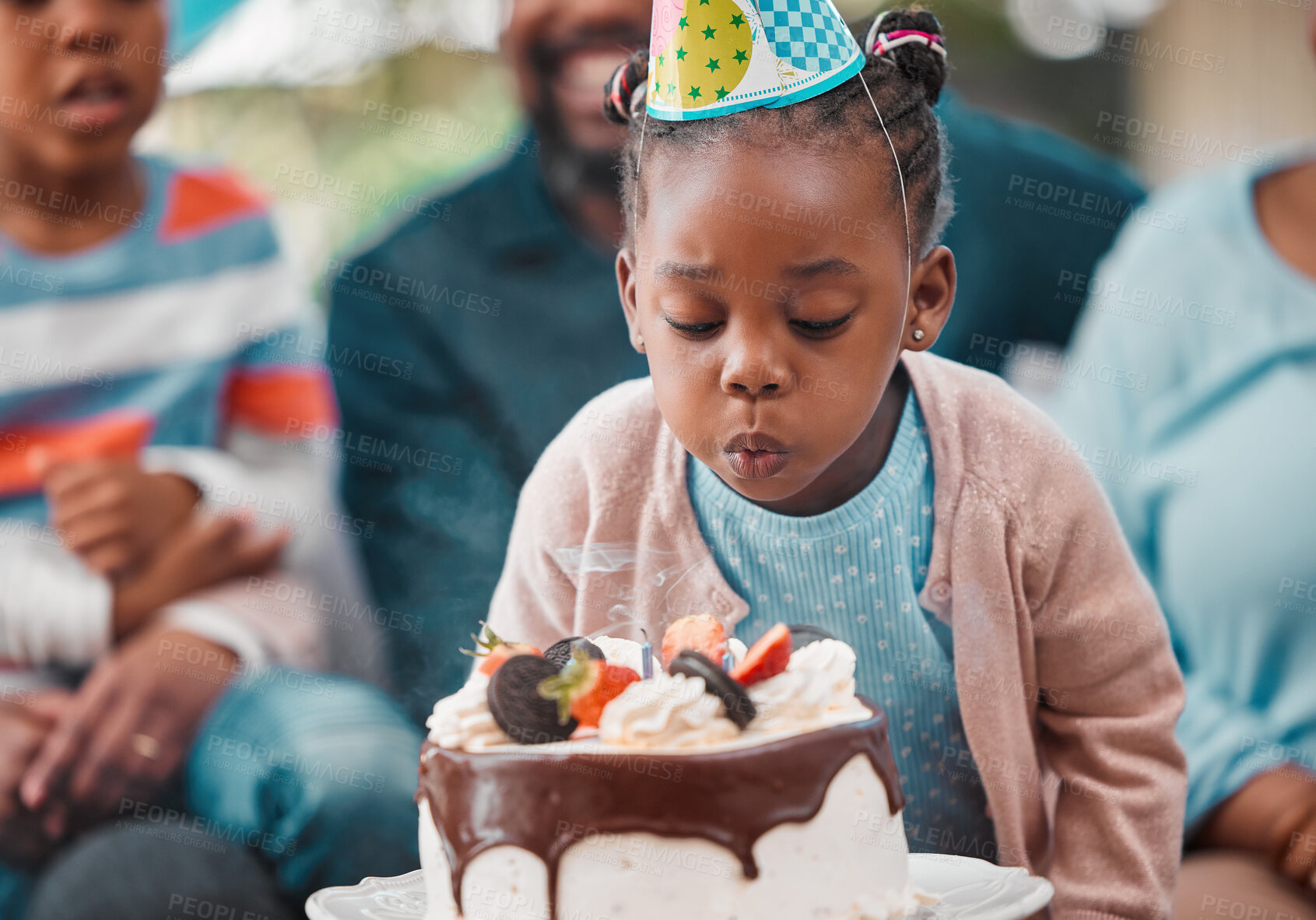 Buy stock photo Shot of an adorable little girl blowing out candles during her birthday party