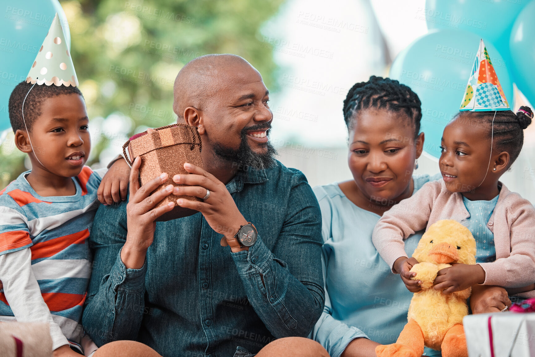 Buy stock photo Black family, children and gift at birthday party with parents, gathering or event in lounge. African people, celebration and excited kid with opening box, happiness and cheerful as community in home