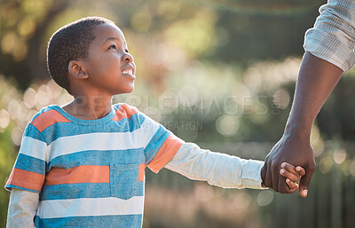 Buy stock photo Shot of a young boy holding on to his father's hand while walking outside