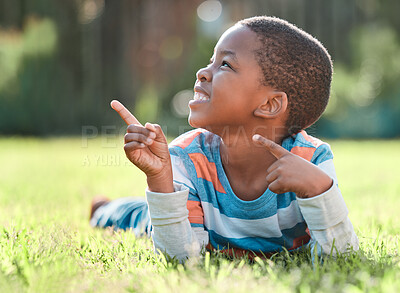 Buy stock photo Shot of a young boy lying on the grass outside