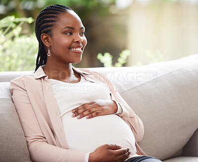 Buy stock photo Cropped shot of an attractive young mother to be looking thoughtful while sitting on the sofa at home