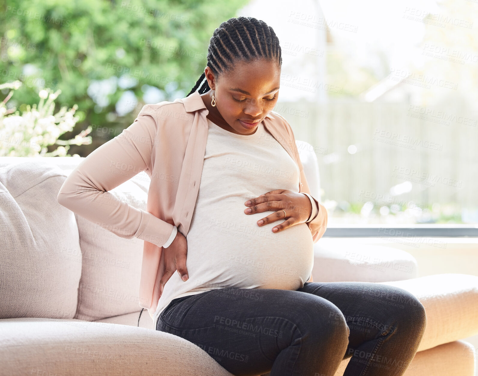 Buy stock photo Back pain, stomach and relax with pregnant woman on sofa for labor, healthcare and maternity. Ache, spine and emergency with African mother in living room of home for pregnancy and uncomfortable 