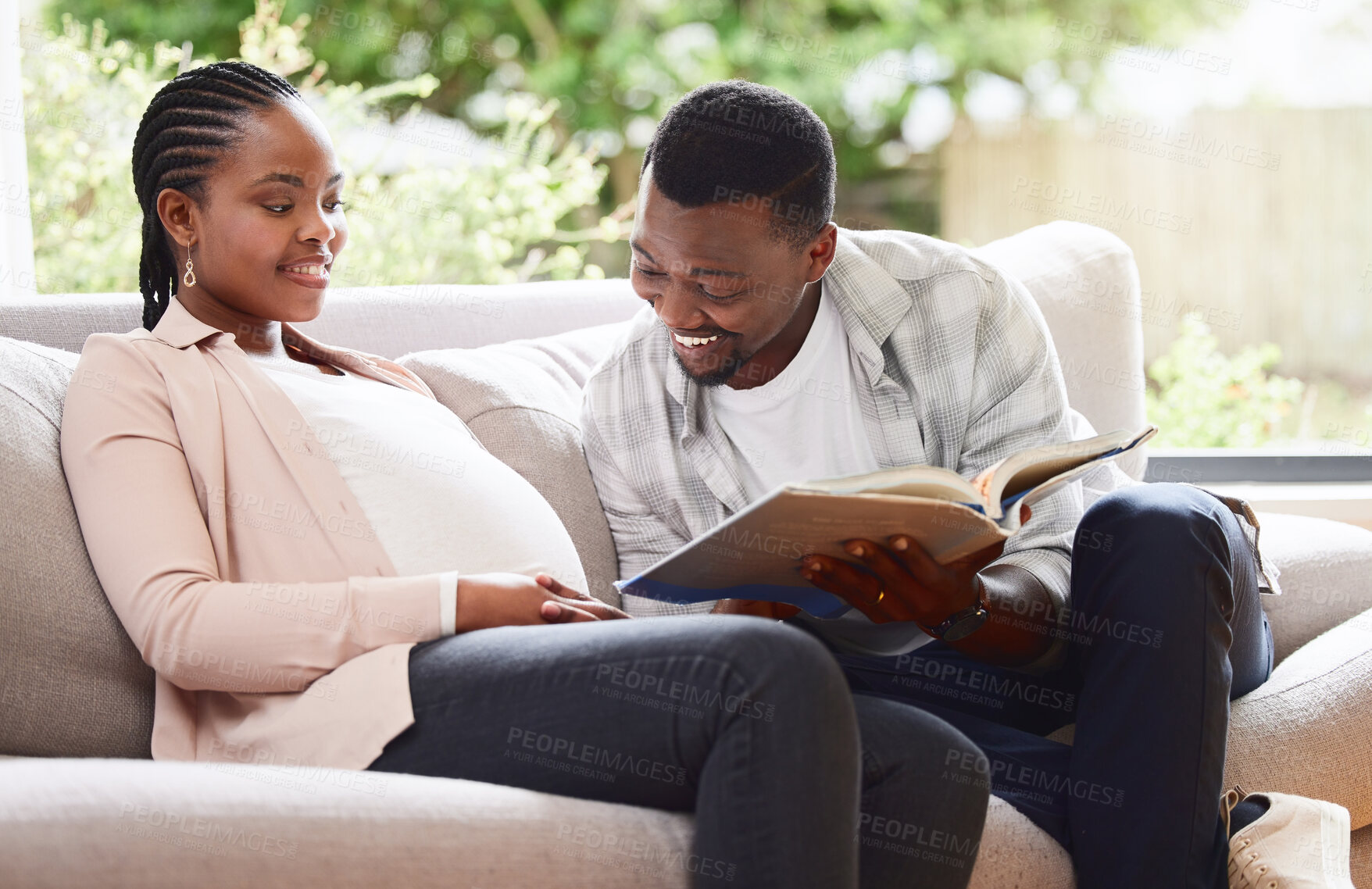 Buy stock photo Pregnant, black couple and relax with book by stomach for prenatal education, care and connection. Happy, woman and man with gynecology info at home for development, advice and support in parenthood