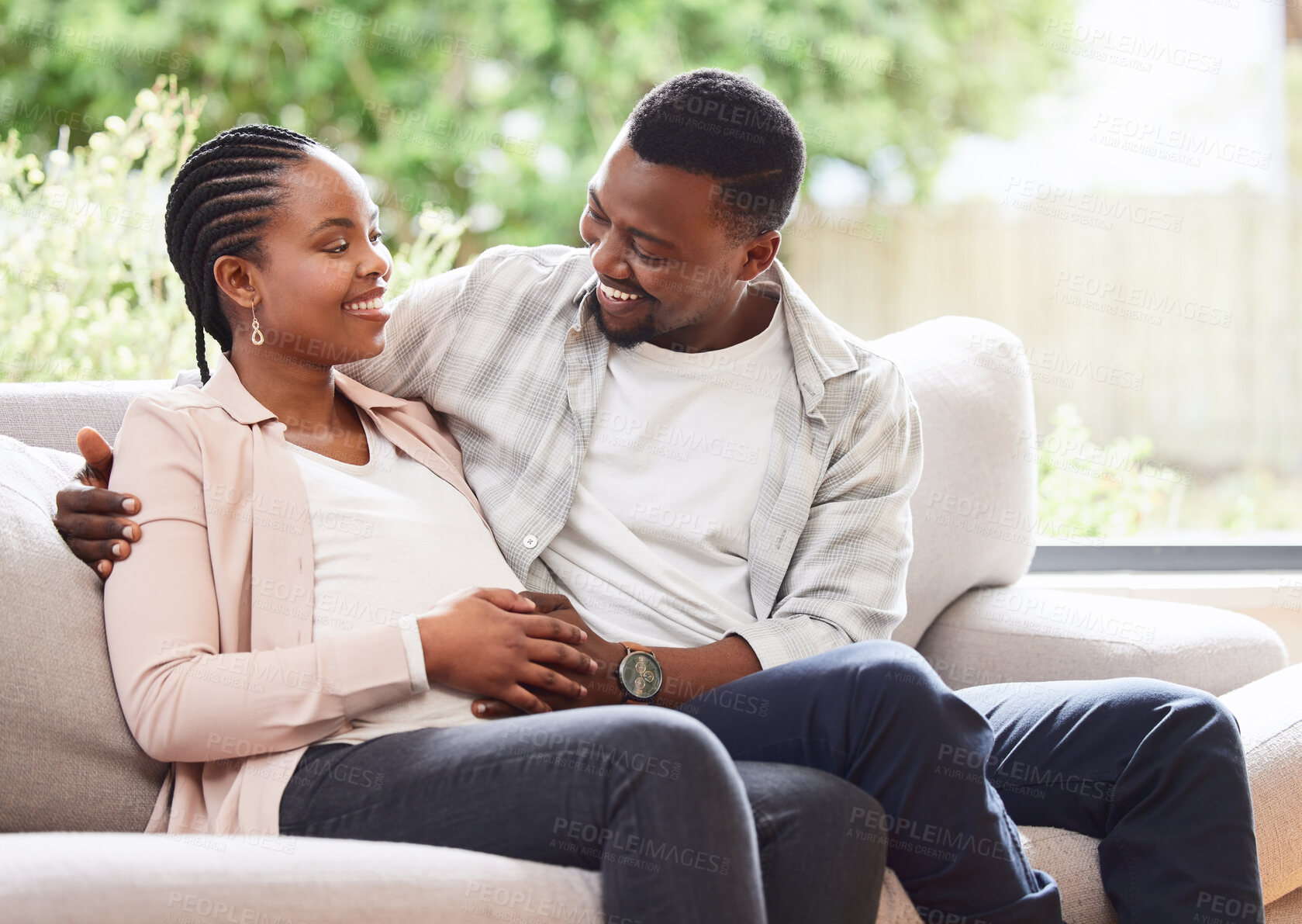 Buy stock photo Black couple, pregnant and hand on stomach for support, love and feeling baby kick in home. Future parents, happy and touch belly in living room for growth, maternity and commitment in relationship