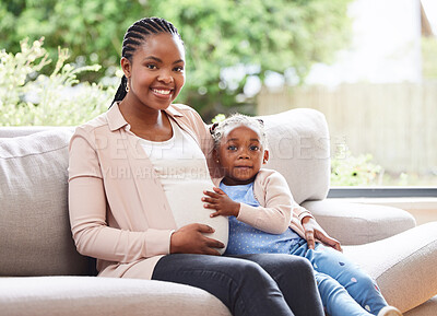 Buy stock photo Cropped portrait of an attractive young pregnant woman and her daughter sitting on the sofa at home