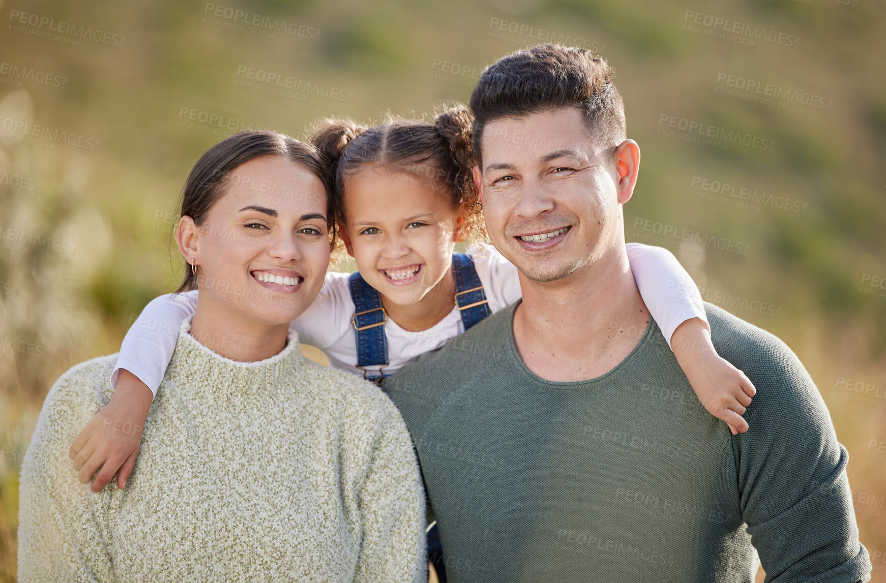 Buy stock photo Shot of a young couple spending time outdoors with their daughter